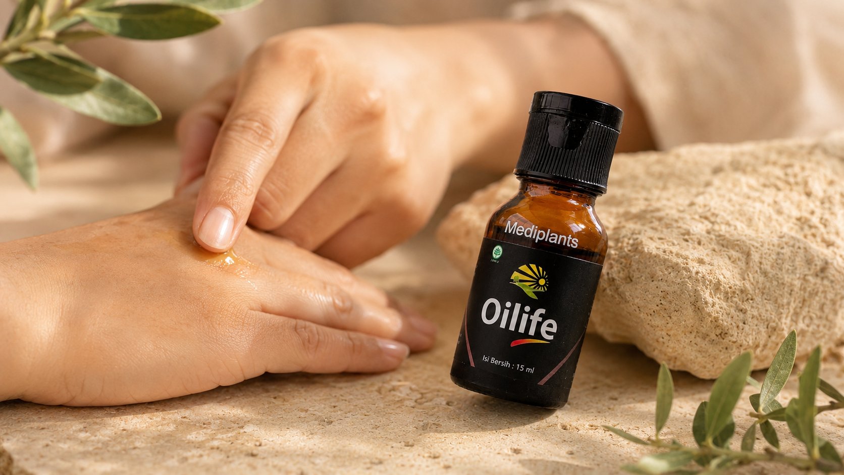 Tangan mengoleskan minyak herbal Oilife pada kulit — produk Oilife BPOM dalam botol 15ml